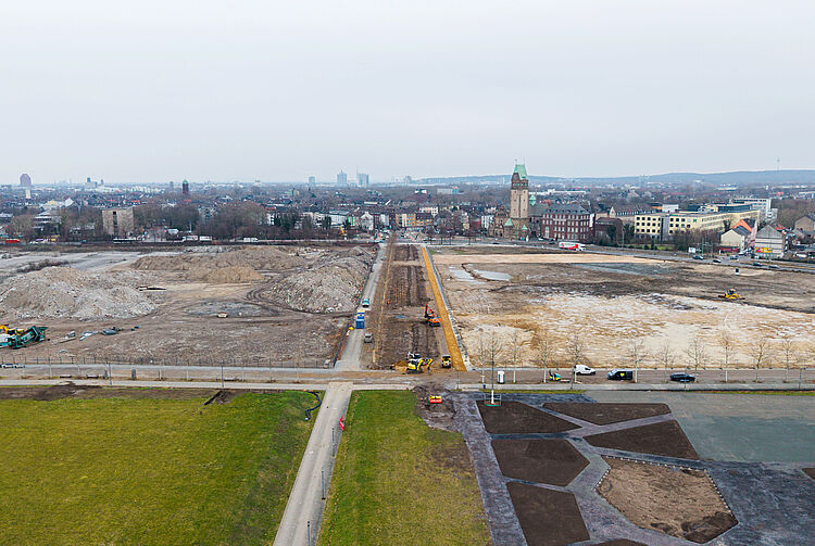 Luftaufnahme der Baustelle mit gerader Straße in der Bildmitte und Duisburg im Hintergrund. Die Straße ist die Hochfeldallee im Februar 2026