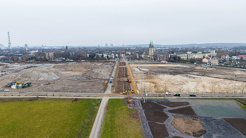 Luftaufnahme der Baustelle mit gerader Straße in der Bildmitte und Duisburg im Hintergrund. Die Straße ist die Hochfeldallee im Februar 2026