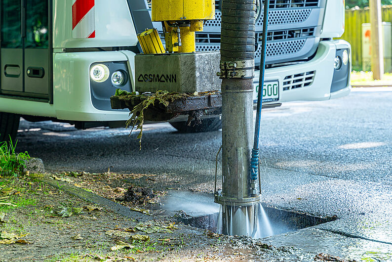 Straßenreinigungsmaschine spritzt Wasser in einen Kanal am Straßenrand
