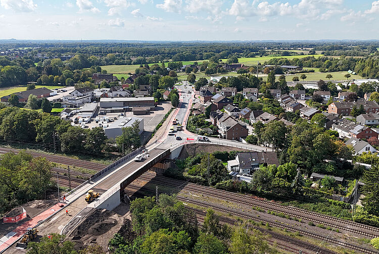 Luftaufnahme der Cölve-Brücke über mehrere Bahngleise, umgeben von Wohnhäusern und viel Grün.